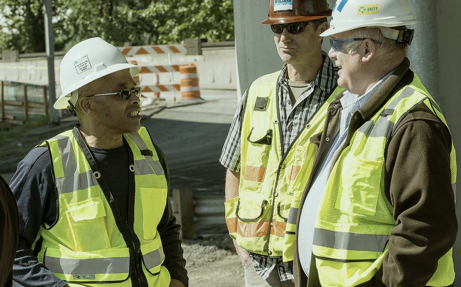 Workers in high-visibility vests and hard hats in discussion on site