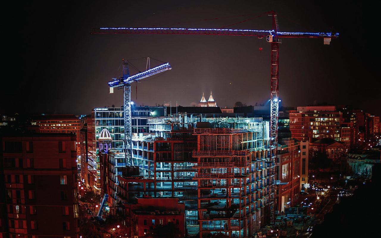 Construction cranes lit up at night over an active site