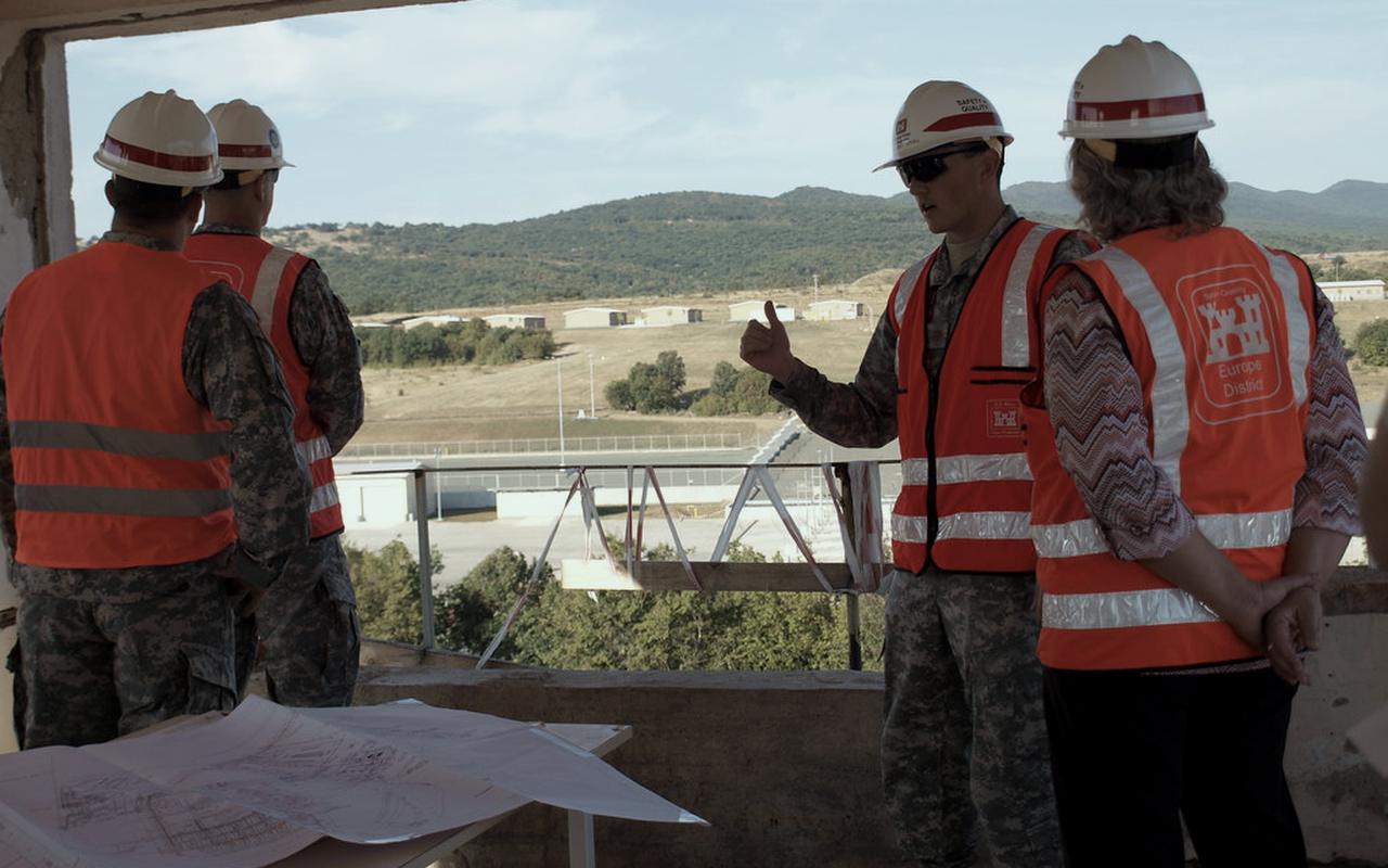A safety team in high-visibility vests reviewing plans while overlooking an active site