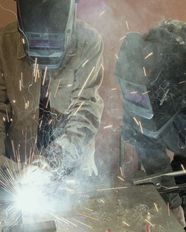 Welders in protective masks working with sparks flying