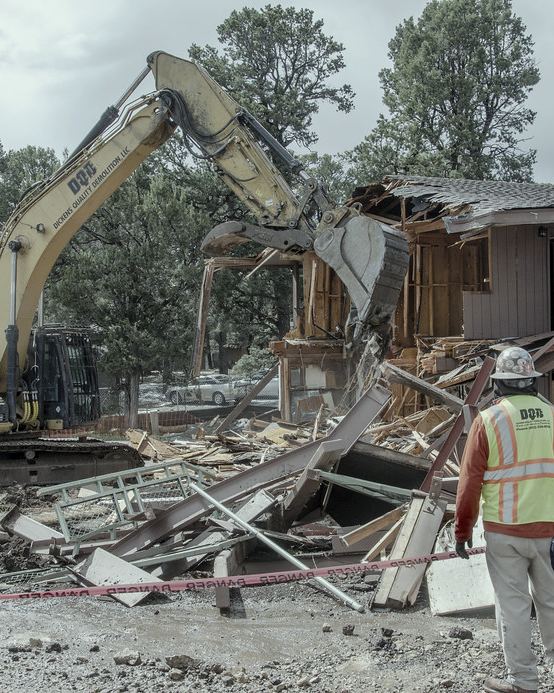 An excavator at work while a spotter in a high-visibility vest watches